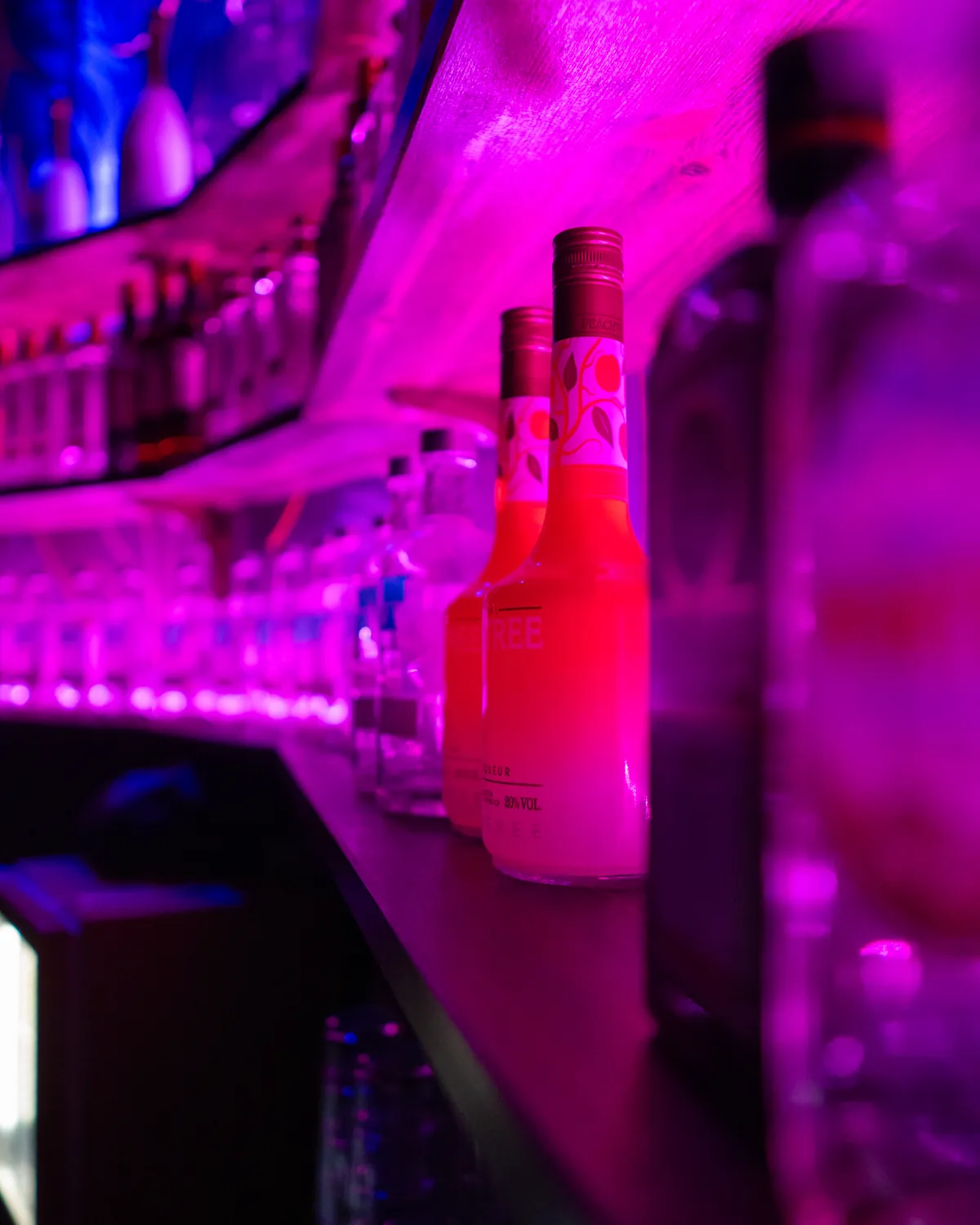 Flaskor på baren i rosa och lila ljus