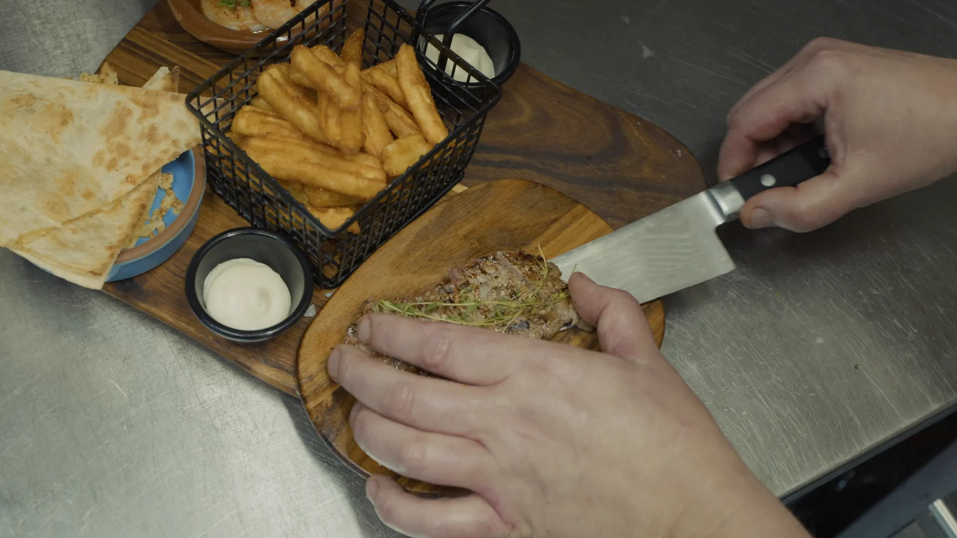 Kocken skär upp biff på en planka med pommes och bröd