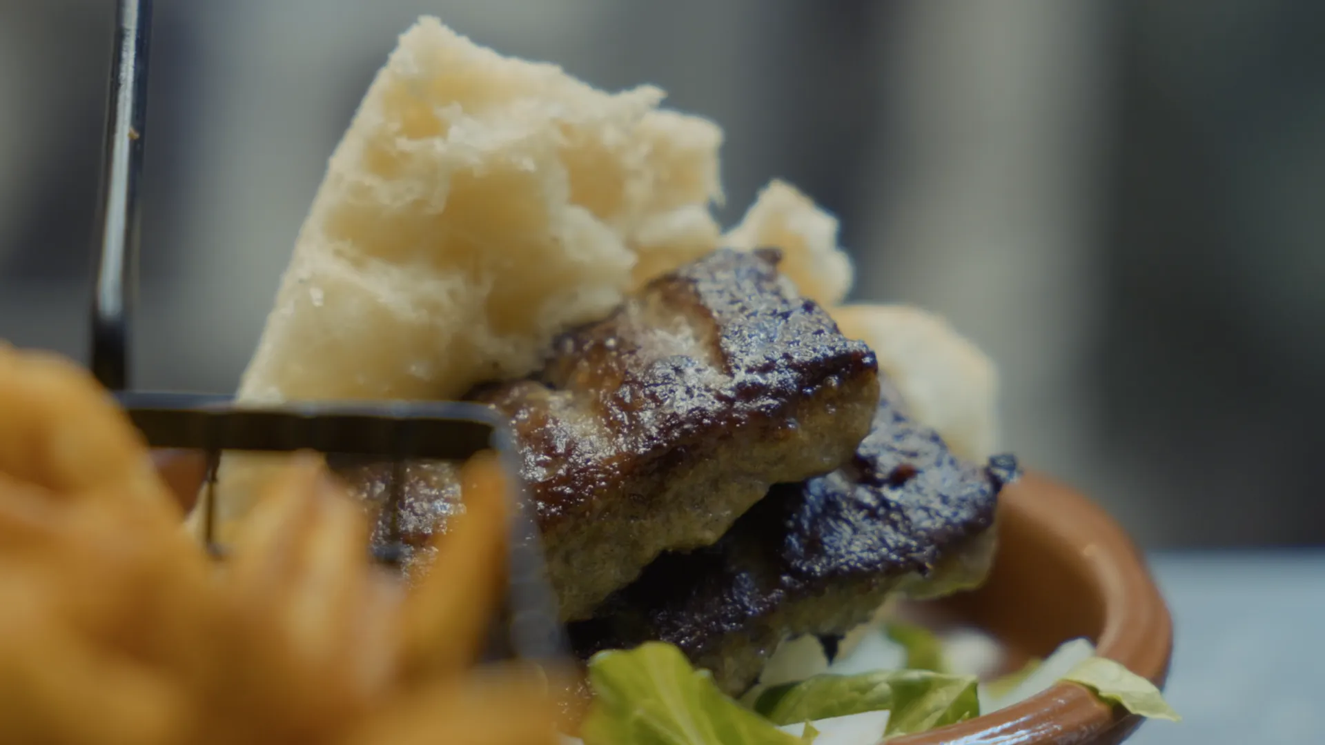 Varm tapasrätt med bröd, kött och pommes i en terrakottaskål