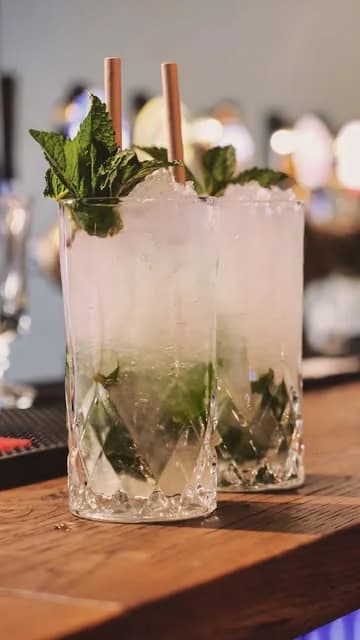 Två mojitos med mynta och sugrör på barbänken