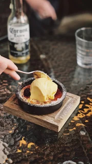 Crema catalán med glass i en svart form, sked på väg ner
