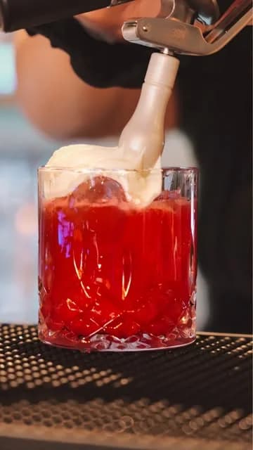 Bartender som häller upp en röd drink i ett kristallglas