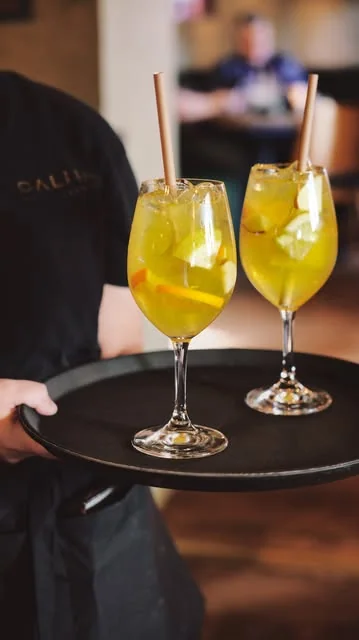 Två gula spritzdrinkar på en svart bricka