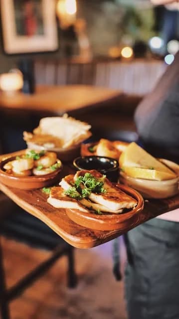 Bricka med tapas: halloumi, ost och bröd i skålar