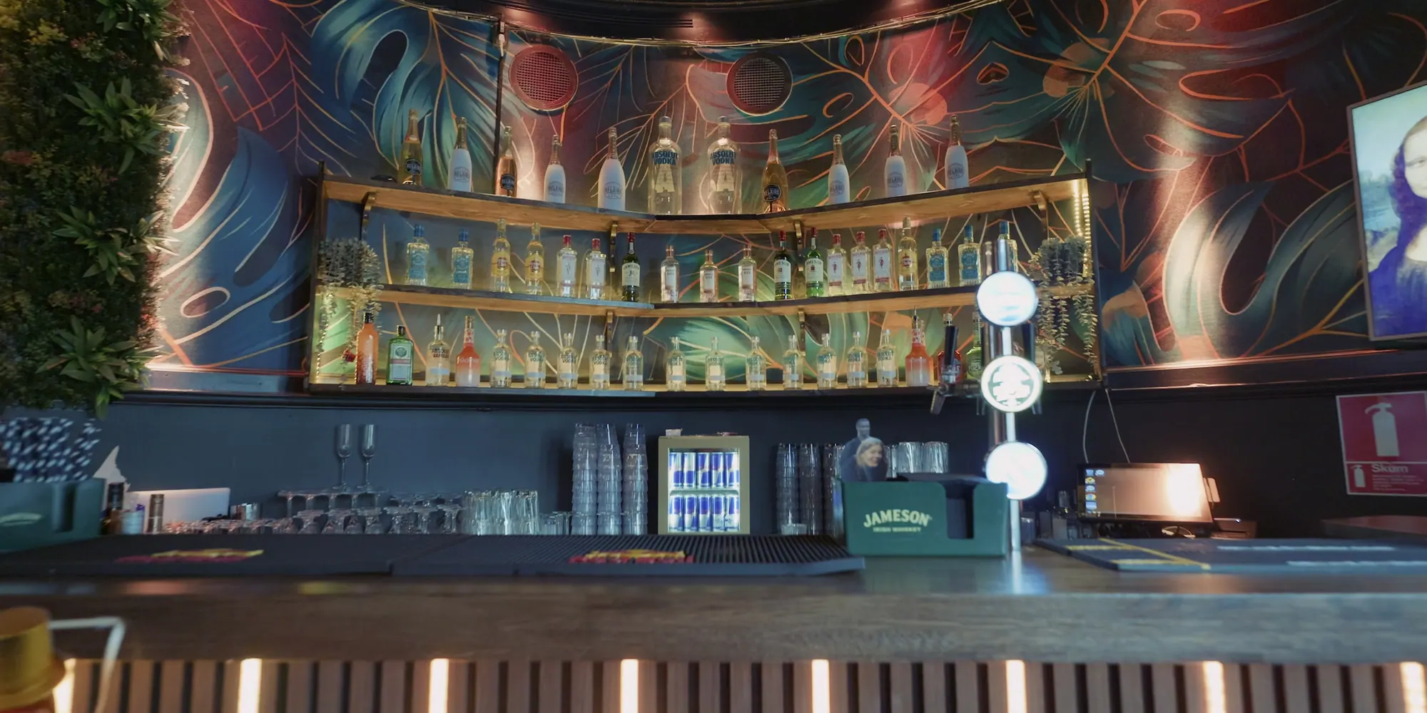 Baren på övervåningen: den målade väggen, flaskorna i hyllorna och de runda lamporna