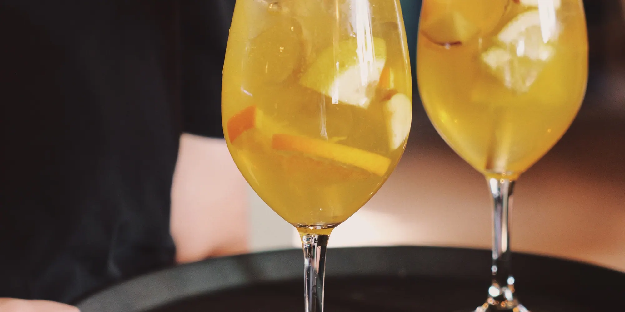 En servitör bär två gyllene spritzar på en bricka
