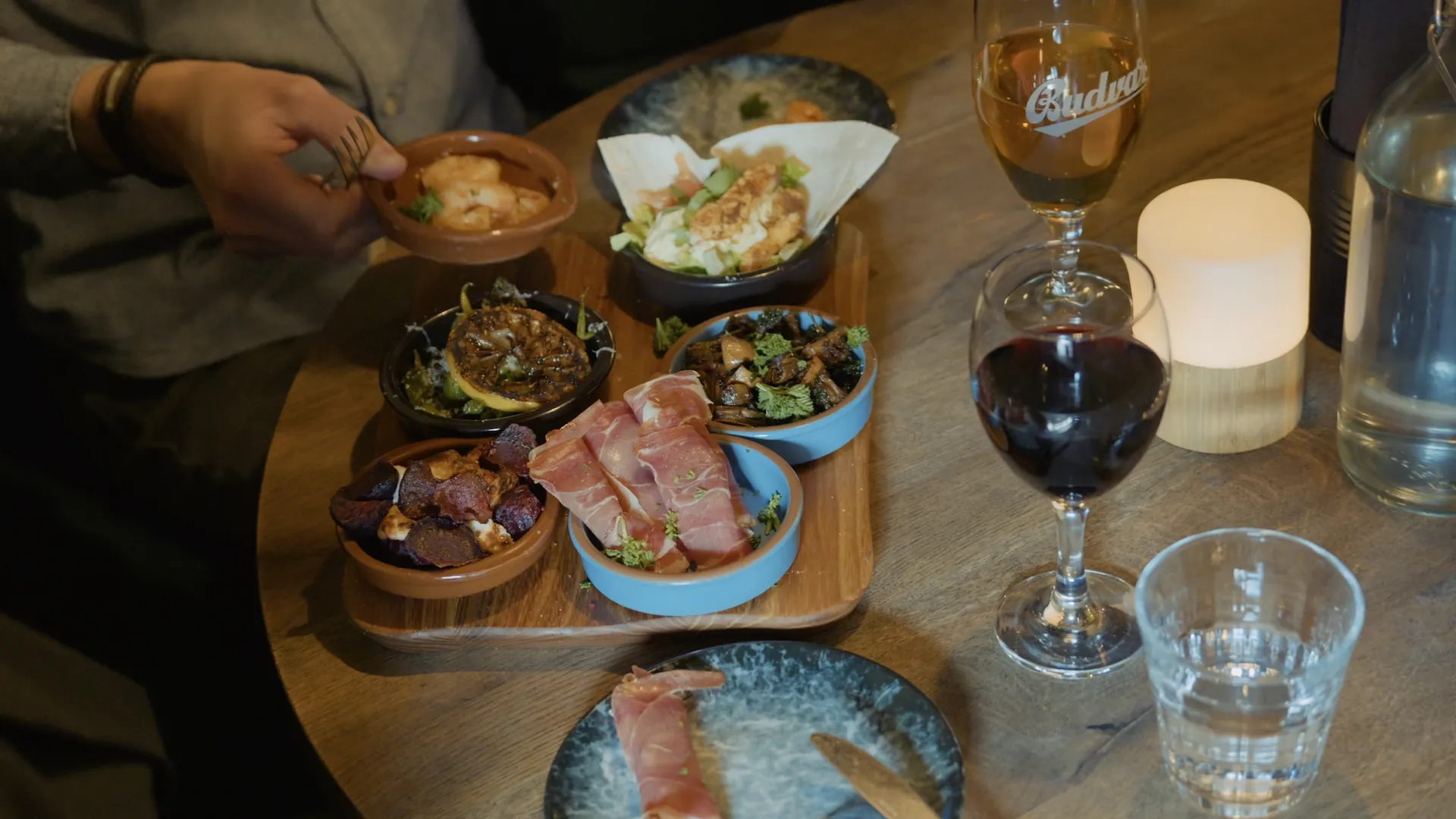 Tapasbordet uppifrån med rött vin, vatten och ett tänt ljus